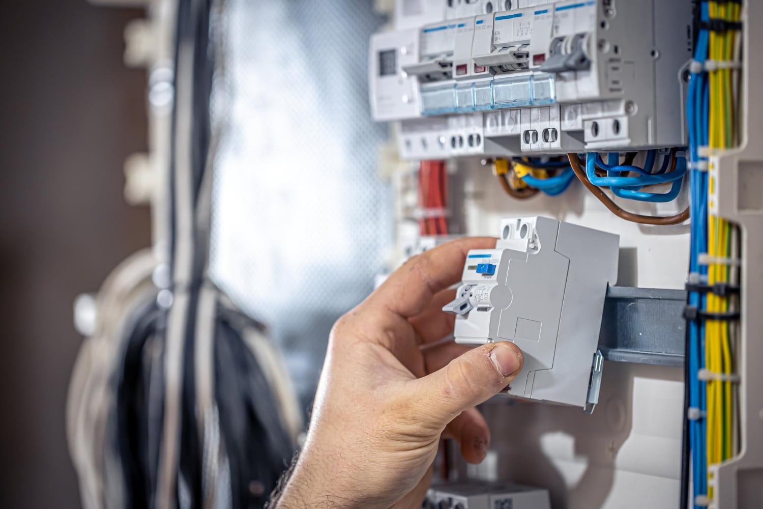 Électricien installant un disjoncteur dans un tableau électrique