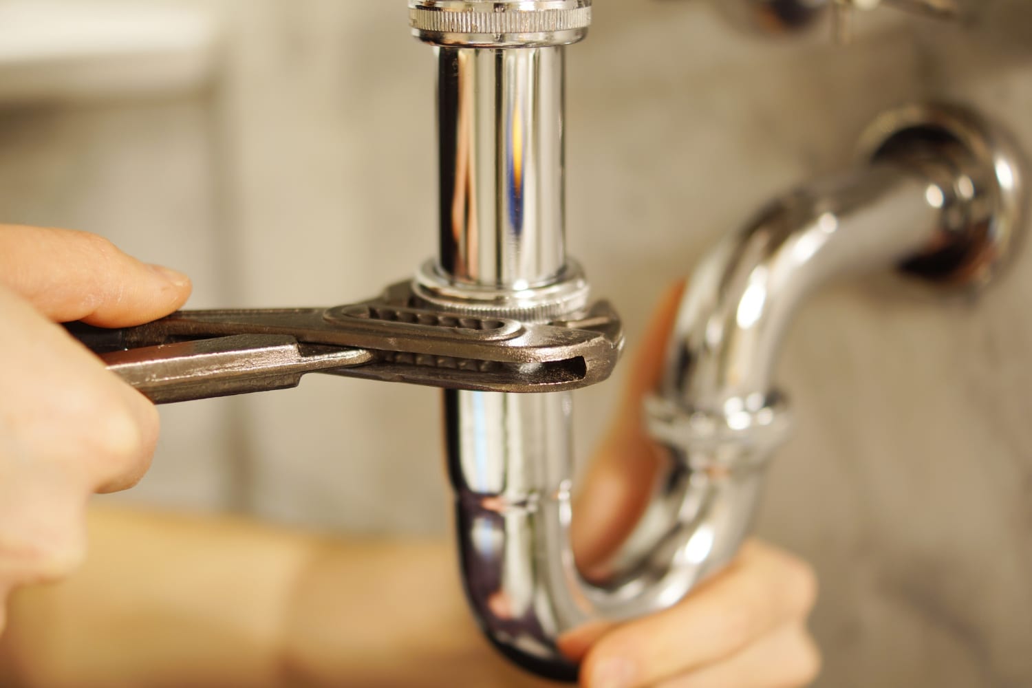 Plombier serrant un siphon chromé avec une clé