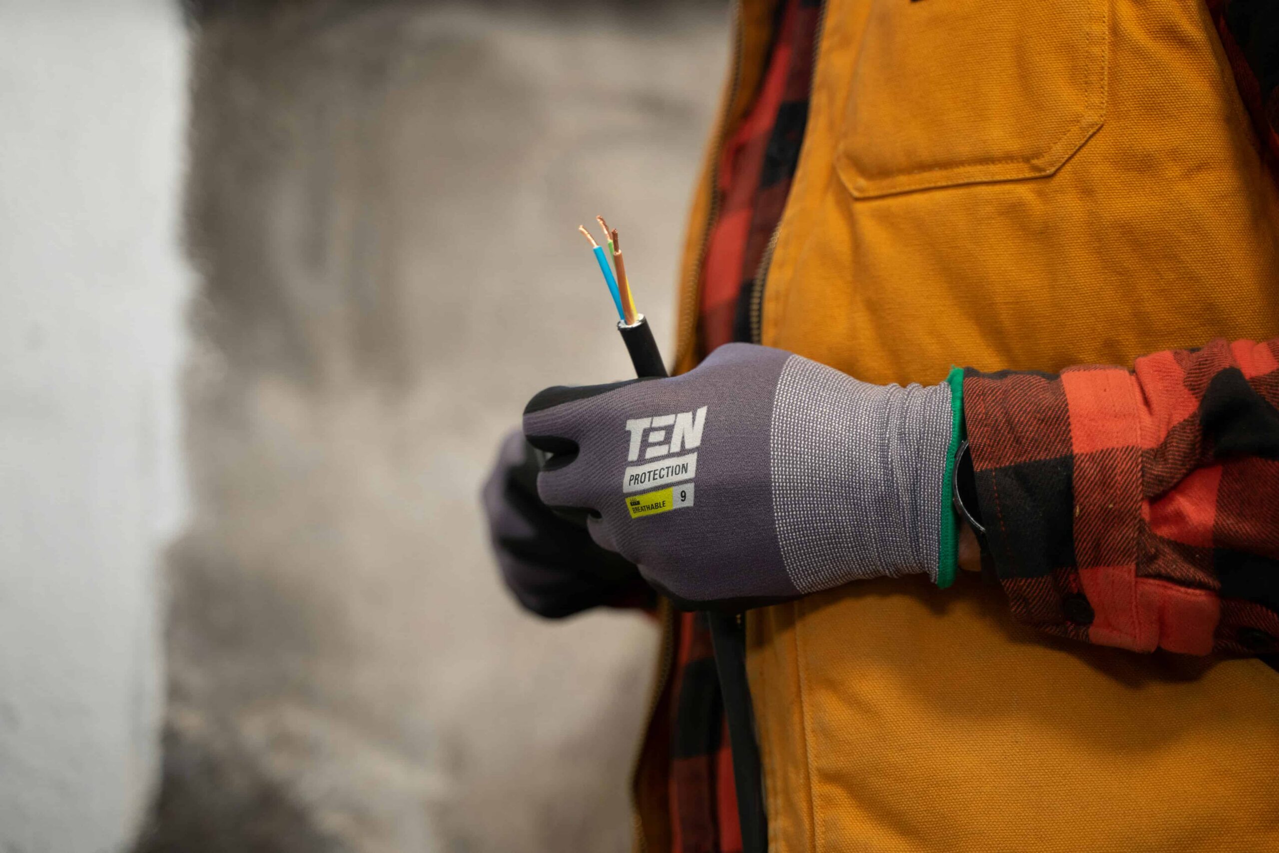Électricien en gants de protection tenant un câble dénudé